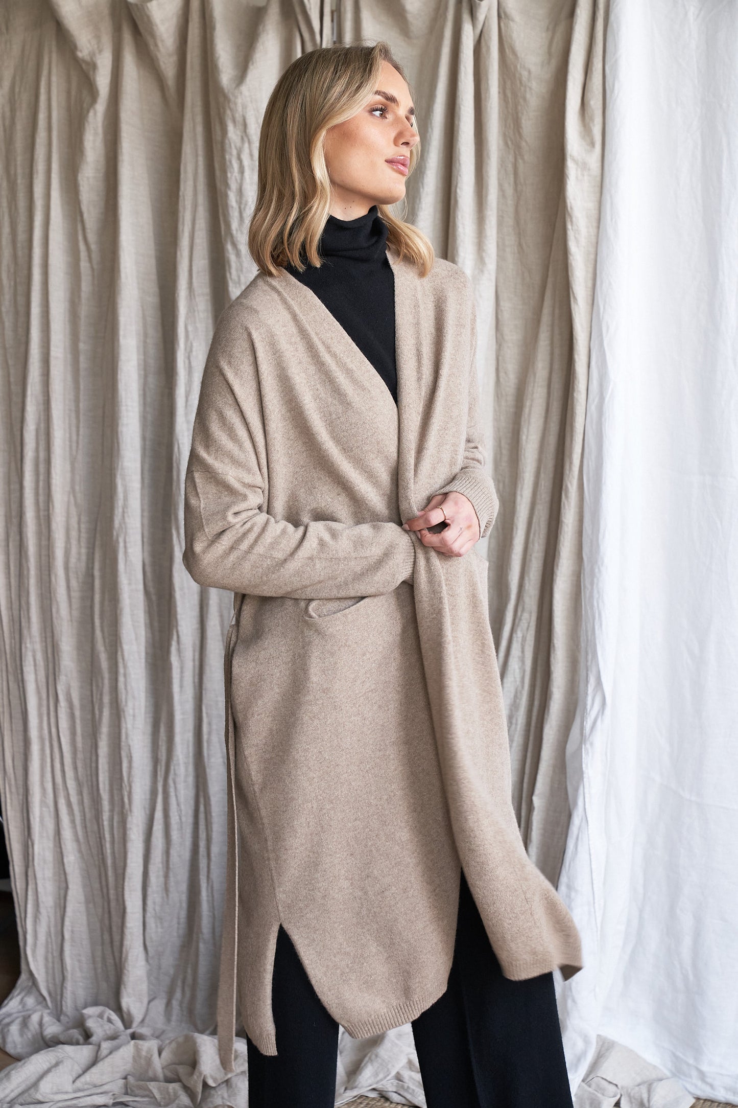 Long Mushroom Cashmere Cardigan with Belt & Pockets – Women’s Coatigan | 100% Pure Cashmere
Wrap yourself in luxury with our long cashmere cardigan in mushroom, designed with a soft belted waist and practical front pockets. Made from 100% pure, ethically sourced cashmere, this elegant coatigan-style knit offers a relaxed, robe-like silhouette perfect for layering during cooler months.
The neutral taupe-grey tone makes it endlessly versatile, while the detachable belt allows for multiple styling options. W